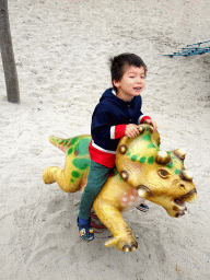 Max riding a Triceratops statue at the playground at Dinoland Zwolle