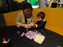Miaomiao and Max making a dinosaur from beads at the T-Rexpedition at Dinoland Zwolle
